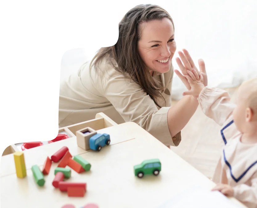 Teacher and child engaging in a playful high-five at Step By Step Nursery in Dubai, fostering early childhood development through interactive learning.