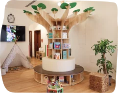 Classroom facility at Step by Step Nursery in Jumeirah, featuring a creative tree-shaped bookshelf with children's books, a cozy teepee, and welcoming decor
